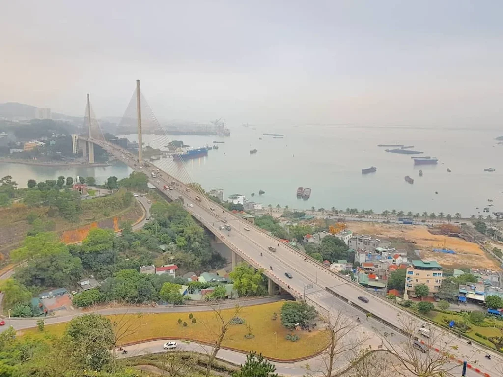Cruising with Danny and Peter, Holland America Line, Westerdam, Halong Bay, Vietnam | A stunning view of the Hạ Long Bay Yacht cruising through emerald waters, surrounded by majestic limestone karsts. Guests enjoy Vietnamese seafood dining on the deck while kayaking in Hạ Long Bay. The private yacht tour showcases the beauty of this UNESCO World Heritage site.