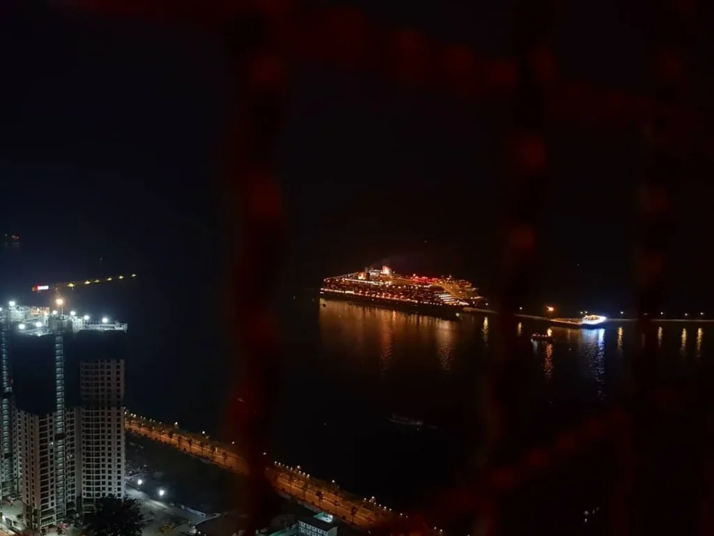 Cruising with Danny and Peter, Holland America Line, Westerdam, Halong Bay, Vietnam | A stunning view of the Hạ Long Bay Yacht cruising through emerald waters, surrounded by majestic limestone karsts. Guests enjoy Vietnamese seafood dining on the deck while kayaking in Hạ Long Bay. The private yacht tour showcases the beauty of this UNESCO World Heritage site.