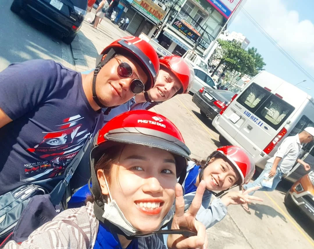 Cruising with Danny and Peter, Holland America Line, Westerdam, Da Nang, Hue, Vietnam | A vibrant street scene in Đà Nẵng showcasing a bustling market filled with fresh produce and aromatic spices, capturing the essence of Vietnamese cuisine. Motorbikes are parked nearby, symbolizing the thrilling motorbike street food tour. An enticing plate of bánh mì and bowls of pho are featured prominently, representing the local street eats enjoyed during this culinary exploration.