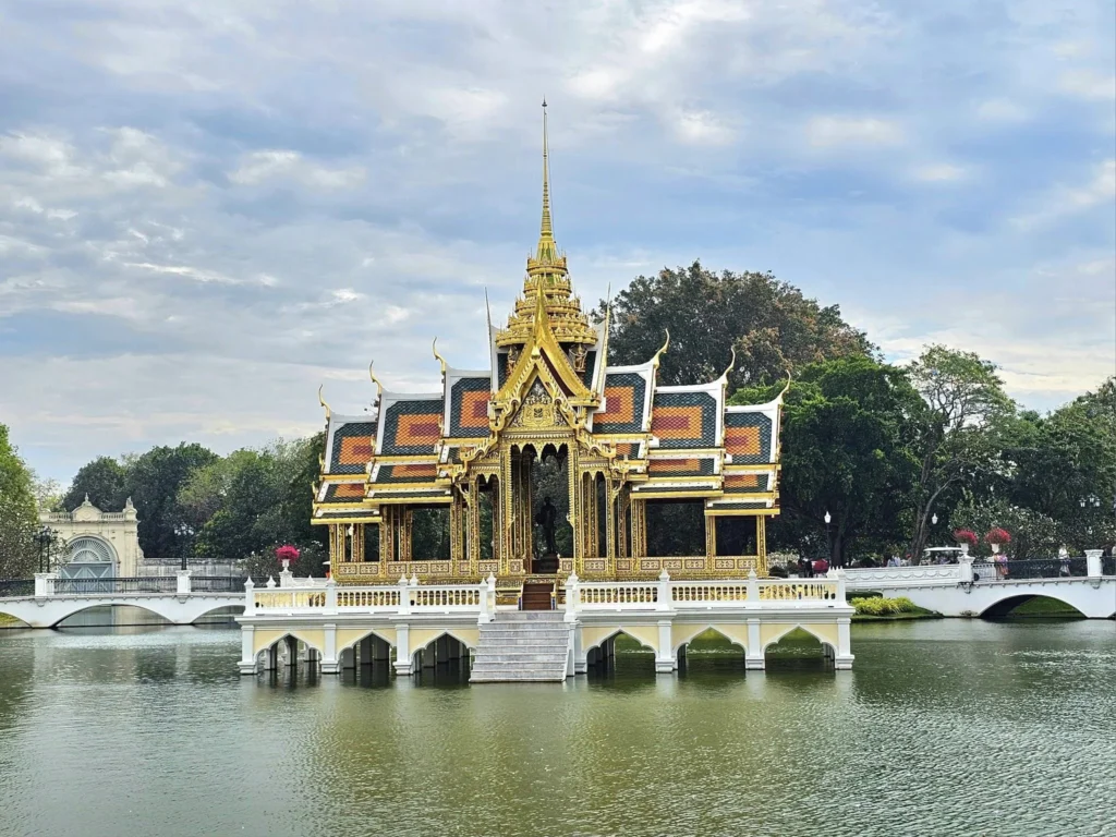 A Majestic Journey: Unveiling the Royal Historical Tour Ayutthaya from the Holland America Cruise 17 Cruising with Danny and Peter, Holland America Line, Westerdam, Laem Chabang, Bangkok, Thailand, Royal Historical Tour Ayutthaya 5 Glorious Stops | Exploring the Royal Historical Tour Ayutthaya and Bang Pa In Ayutthaya with lush gardens at Bang Pa In Palace, the elegant Aisawan Dhipaya Pavilion on a tranquil lake, towering stupa and Buddha statues at Ayutthaya Temples, colorful Traditional Thai Cuisine, and the iconic Buddha head in tree roots at Wat Mahathat Ruins—a UNESCO Heritage Site—all part of an unforgettable Thailand Cultural Tour and Ayutthaya Day Trip from the Holland America Cruise, showcasing Thai Royal History.