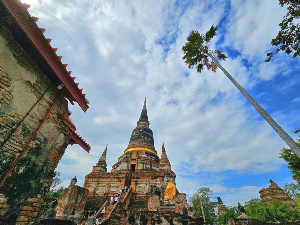 A Majestic Journey: Unveiling the Royal Historical Tour Ayutthaya from the Holland America Cruise 40 Cruising with Danny and Peter, Holland America Line, Westerdam, Laem Chabang, Bangkok, Thailand, Royal Historical Tour Ayutthaya 5 Glorious Stops | Exploring the Royal Historical Tour Ayutthaya and Bang Pa In Ayutthaya with lush gardens at Bang Pa In Palace, the elegant Aisawan Dhipaya Pavilion on a tranquil lake, towering stupa and Buddha statues at Ayutthaya Temples, colorful Traditional Thai Cuisine, and the iconic Buddha head in tree roots at Wat Mahathat Ruins—a UNESCO Heritage Site—all part of an unforgettable Thailand Cultural Tour and Ayutthaya Day Trip from the Holland America Cruise, showcasing Thai Royal History.