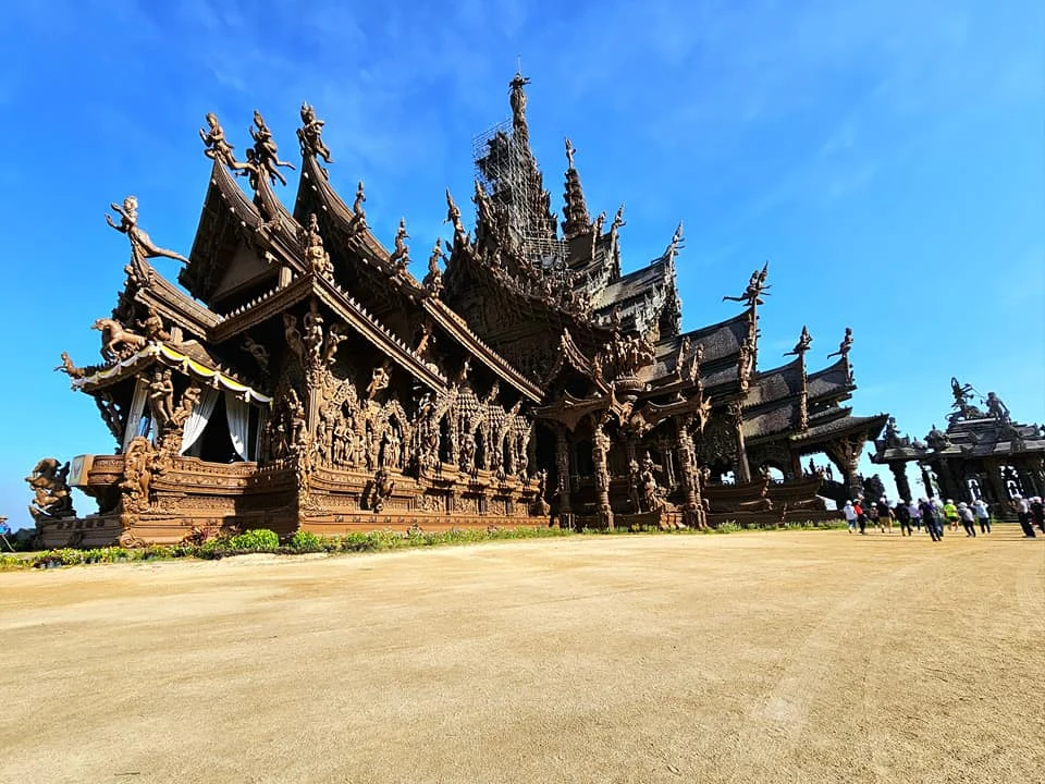 Cruising with Danny and Peter, Holland America Line, Westerdam, Laem Chabang, Bangkok, Thailand, Sanctuary Of Truth Pattaya Wonders | "Facade of the Sanctuary of Truth Pattaya showcasing intricate Thai Craftsmanship Art with towering wooden spires against a lush coastal backdrop, featuring detailed wooden carvings inside the Wooden Temple Pattaya depicting Buddhist Hindu Architecture and mythological scenes. The central hall houses a majestic wooden sculpture of a celestial deity, a highlight of Spiritual Sites Thailand and Thai Cultural Heritage. The luxurious Holland America Westerdam docked at Laem Chabang offers a Laem Chabang Excursion to explore Pattaya Cultural Landmarks, while lush greenery surrounds this Pattaya Tourist Attraction inspired by Ayutthaya Kingdom Design.