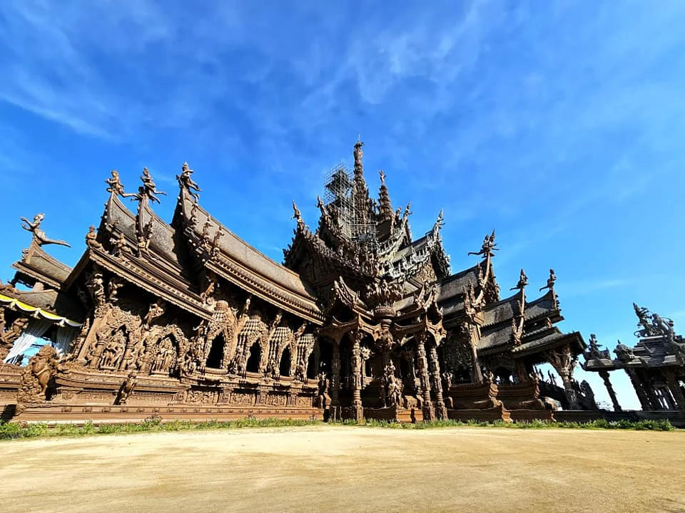 Cruising with Danny and Peter, Holland America Line, Westerdam, Laem Chabang, Bangkok, Thailand, Sanctuary Of Truth Pattaya Wonders | "Facade of the Sanctuary of Truth Pattaya showcasing intricate Thai Craftsmanship Art with towering wooden spires against a lush coastal backdrop, featuring detailed wooden carvings inside the Wooden Temple Pattaya depicting Buddhist Hindu Architecture and mythological scenes. The central hall houses a majestic wooden sculpture of a celestial deity, a highlight of Spiritual Sites Thailand and Thai Cultural Heritage. The luxurious Holland America Westerdam docked at Laem Chabang offers a Laem Chabang Excursion to explore Pattaya Cultural Landmarks, while lush greenery surrounds this Pattaya Tourist Attraction inspired by Ayutthaya Kingdom Design.