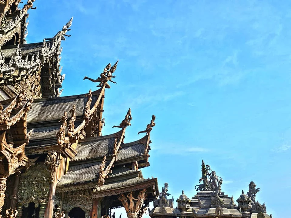 Cruising with Danny and Peter, Holland America Line, Westerdam, Laem Chabang, Bangkok, Thailand, Sanctuary Of Truth Pattaya Wonders | "Facade of the Sanctuary of Truth Pattaya showcasing intricate Thai Craftsmanship Art with towering wooden spires against a lush coastal backdrop, featuring detailed wooden carvings inside the Wooden Temple Pattaya depicting Buddhist Hindu Architecture and mythological scenes. The central hall houses a majestic wooden sculpture of a celestial deity, a highlight of Spiritual Sites Thailand and Thai Cultural Heritage. The luxurious Holland America Westerdam docked at Laem Chabang offers a Laem Chabang Excursion to explore Pattaya Cultural Landmarks, while lush greenery surrounds this Pattaya Tourist Attraction inspired by Ayutthaya Kingdom Design.