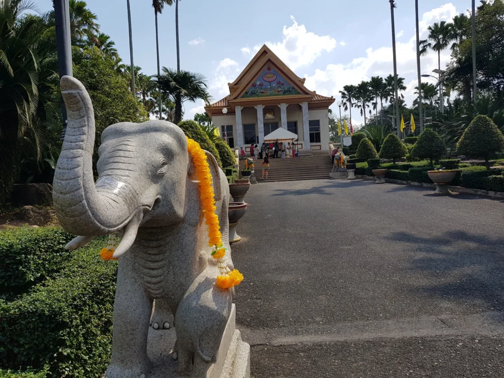 Cruising with Danny and Peter, Holland America Line, Westerdam, Laem Chabang, Bangkok, Thailand | A serene view of Wat Yan Nasangwararam temple in Pattaya, showcasing intricate Thai architecture surrounded by lush greenery. In the foreground, worshippers engage in meditation and tranquility, while the majestic Khao Chi Chan Buddha monument looms in the background, radiating serenity. This scene captures the essence of a spiritual journey in Pattaya, highlighting the cultural heritage of Thai Buddhism and the beauty of religious art in Thailand.