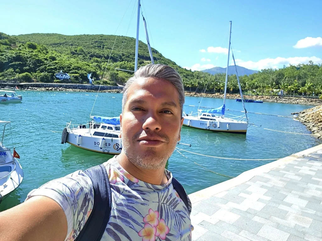 Cruising with Danny and Peter, Holland America Line, Westerdam, Nha Trang, Vietnam, Nha Trang Island Escapade Adventure | Group of tourists enjoying a Nha Trang Island Escapade Adventure featuring Mieu Island Exploration under a tropical sun, vibrant underwater scenes from Coral Reef Snorkeling in Nha Trang Bay, the pirate ship-shaped Tri Nguyen Aquarium showcasing a Marine Life Experience on a Vietnam Coastal Adventure, local fishermen feeding groupers during a Fishing Village Visit, relaxing on golden sands at Mini Beach Relaxation after a Nha Trang Island Tour with Holland America Cruise, and a scenic view of Nha Trang Bay from a boat during a Tropical Island Retreat.