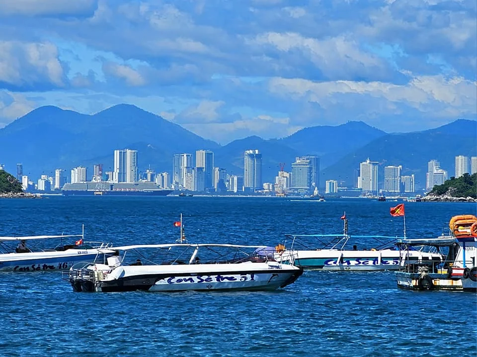Cruising with Danny and Peter, Holland America Line, Westerdam, Nha Trang, Vietnam, Nha Trang Island Escapade Adventure | Group of tourists enjoying a Nha Trang Island Escapade Adventure featuring Mieu Island Exploration under a tropical sun, vibrant underwater scenes from Coral Reef Snorkeling in Nha Trang Bay, the pirate ship-shaped Tri Nguyen Aquarium showcasing a Marine Life Experience on a Vietnam Coastal Adventure, local fishermen feeding groupers during a Fishing Village Visit, relaxing on golden sands at Mini Beach Relaxation after a Nha Trang Island Tour with Holland America Cruise, and a scenic view of Nha Trang Bay from a boat during a Tropical Island Retreat.