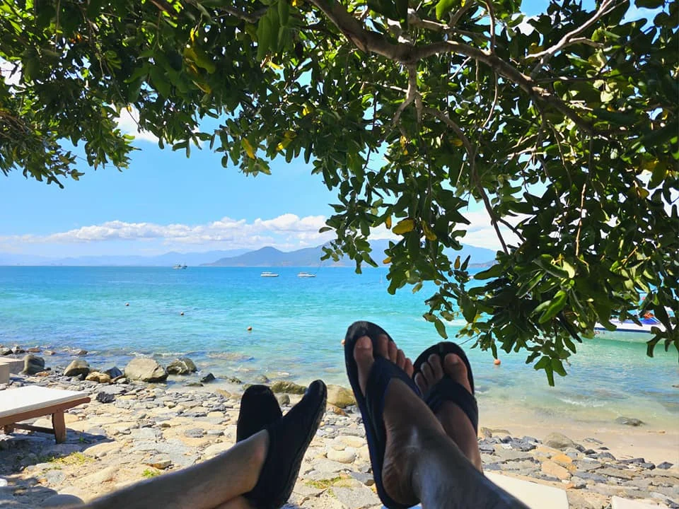 Cruising with Danny and Peter, Holland America Line, Westerdam, Nha Trang, Vietnam, Nha Trang Island Escapade Adventure | Group of tourists enjoying a Nha Trang Island Escapade Adventure featuring Mieu Island Exploration under a tropical sun, vibrant underwater scenes from Coral Reef Snorkeling in Nha Trang Bay, the pirate ship-shaped Tri Nguyen Aquarium showcasing a Marine Life Experience on a Vietnam Coastal Adventure, local fishermen feeding groupers during a Fishing Village Visit, relaxing on golden sands at Mini Beach Relaxation after a Nha Trang Island Tour with Holland America Cruise, and a scenic view of Nha Trang Bay from a boat during a Tropical Island Retreat.