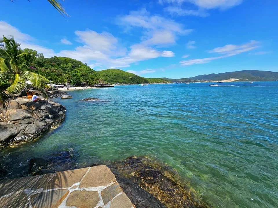 Cruising with Danny and Peter, Holland America Line, Westerdam, Nha Trang, Vietnam, Nha Trang Island Escapade Adventure | Group of tourists enjoying a Nha Trang Island Escapade Adventure featuring Mieu Island Exploration under a tropical sun, vibrant underwater scenes from Coral Reef Snorkeling in Nha Trang Bay, the pirate ship-shaped Tri Nguyen Aquarium showcasing a Marine Life Experience on a Vietnam Coastal Adventure, local fishermen feeding groupers during a Fishing Village Visit, relaxing on golden sands at Mini Beach Relaxation after a Nha Trang Island Tour with Holland America Cruise, and a scenic view of Nha Trang Bay from a boat during a Tropical Island Retreat.