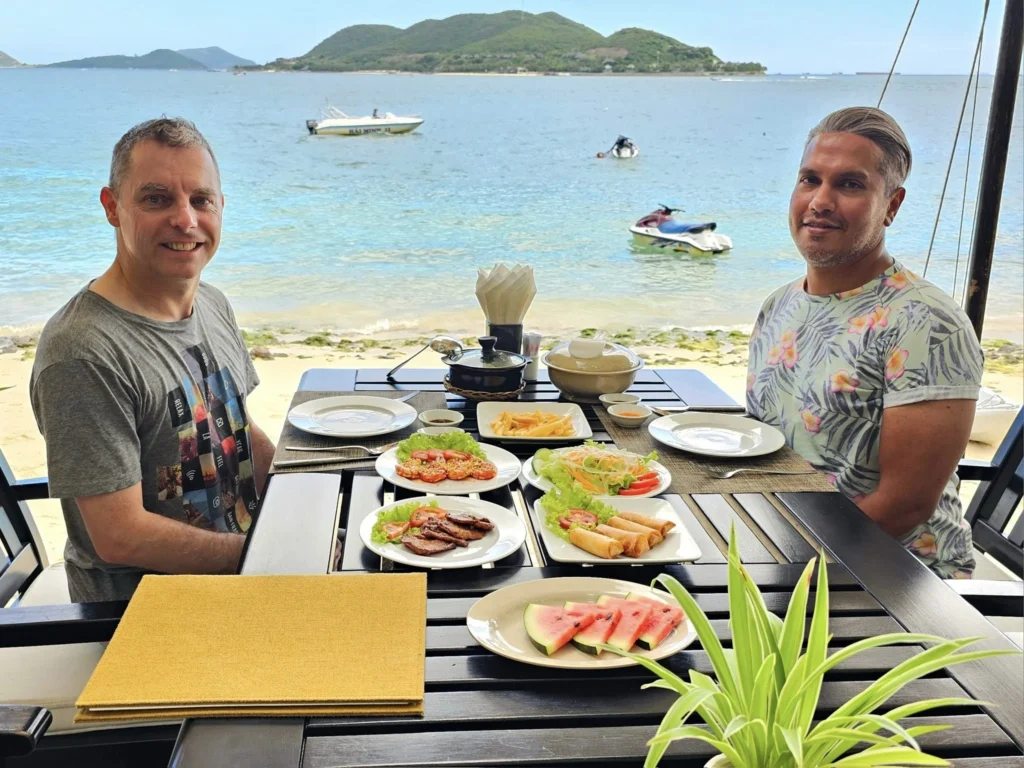 Cruising with Danny and Peter, Holland America Line, Westerdam, Nha Trang, Vietnam, Nha Trang Island Escapade Adventure | Group of tourists enjoying a Nha Trang Island Escapade Adventure featuring Mieu Island Exploration under a tropical sun, vibrant underwater scenes from Coral Reef Snorkeling in Nha Trang Bay, the pirate ship-shaped Tri Nguyen Aquarium showcasing a Marine Life Experience on a Vietnam Coastal Adventure, local fishermen feeding groupers during a Fishing Village Visit, relaxing on golden sands at Mini Beach Relaxation after a Nha Trang Island Tour with Holland America Cruise, and a scenic view of Nha Trang Bay from a boat during a Tropical Island Retreat.