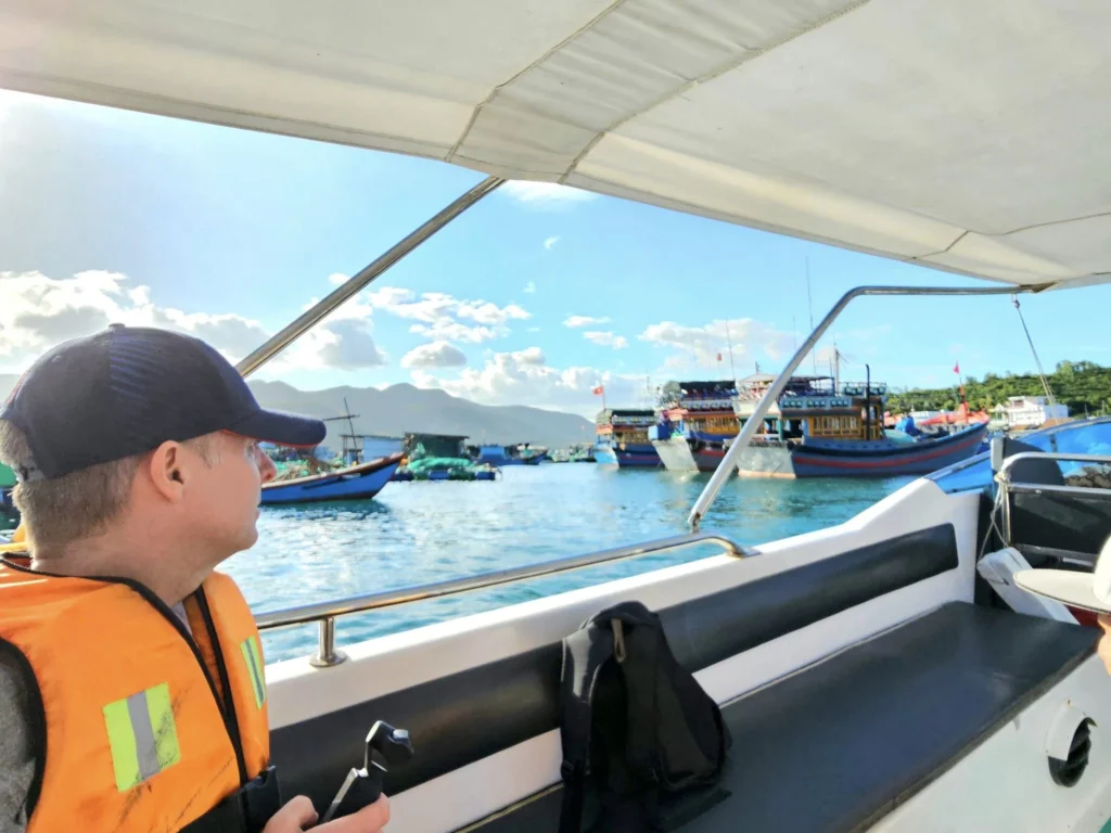 Cruising with Danny and Peter, Holland America Line, Westerdam, Nha Trang, Vietnam, Nha Trang Island Escapade Adventure | Group of tourists enjoying a Nha Trang Island Escapade Adventure featuring Mieu Island Exploration under a tropical sun, vibrant underwater scenes from Coral Reef Snorkeling in Nha Trang Bay, the pirate ship-shaped Tri Nguyen Aquarium showcasing a Marine Life Experience on a Vietnam Coastal Adventure, local fishermen feeding groupers during a Fishing Village Visit, relaxing on golden sands at Mini Beach Relaxation after a Nha Trang Island Tour with Holland America Cruise, and a scenic view of Nha Trang Bay from a boat during a Tropical Island Retreat.