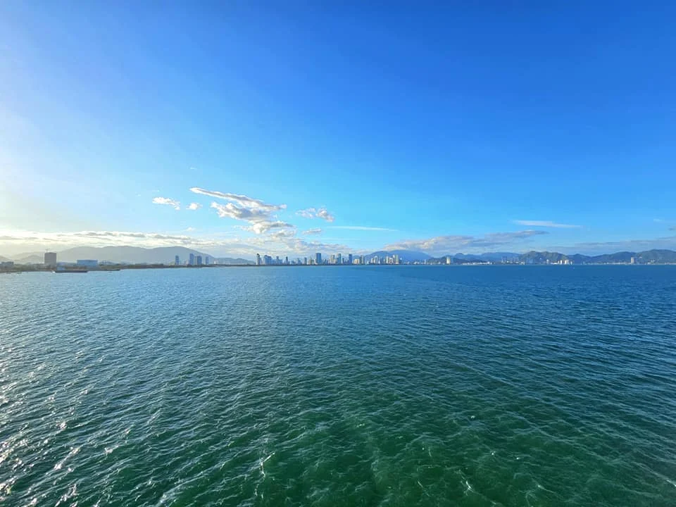 Cruising with Danny and Peter, Holland America Line, Westerdam, Nha Trang, Vietnam, Nha Trang Island Escapade Adventure | Group of tourists enjoying a Nha Trang Island Escapade Adventure featuring Mieu Island Exploration under a tropical sun, vibrant underwater scenes from Coral Reef Snorkeling in Nha Trang Bay, the pirate ship-shaped Tri Nguyen Aquarium showcasing a Marine Life Experience on a Vietnam Coastal Adventure, local fishermen feeding groupers during a Fishing Village Visit, relaxing on golden sands at Mini Beach Relaxation after a Nha Trang Island Tour with Holland America Cruise, and a scenic view of Nha Trang Bay from a boat during a Tropical Island Retreat.