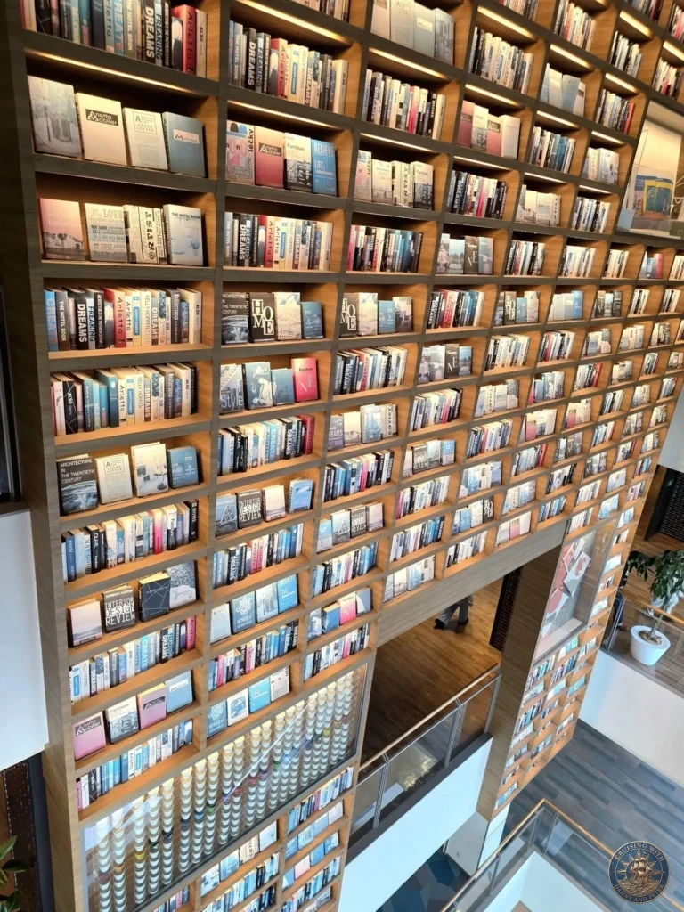 Massive two-story wooden bookshelf wall filled with thousands of books at Mirai Nagasaki Coco Walk in Nagasaki Japan cruise port guide. A unique architectural feature and popular thing to do in Nagasaki from cruise ship, perfect for one day in Nagasaki Japan itinerary when exploring near the Ferris wheel and waterfront from the Westerdam by Danny and Peter.