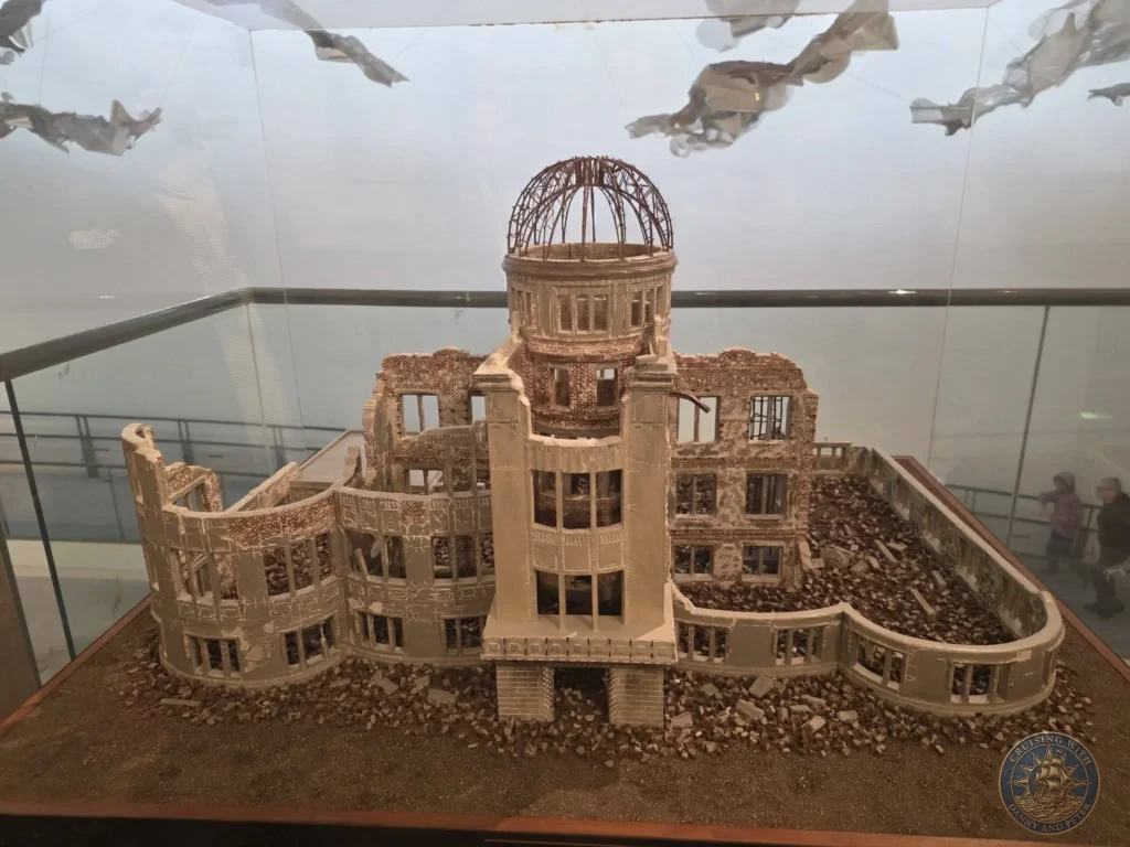 Detailed scale model of the ruins of Urakami Cathedral at the Nagasaki Atomic Bomb Museum, showing the devastated brick structure with its iconic dome skeleton. The model is displayed under glass with debris scattered around the base. Featured in Nagasaki Japan cruise port guide, things to do in Nagasaki from cruise ship, and one day in Nagasaki Japan itinerary from the Westerdam. by Danny and Peter.