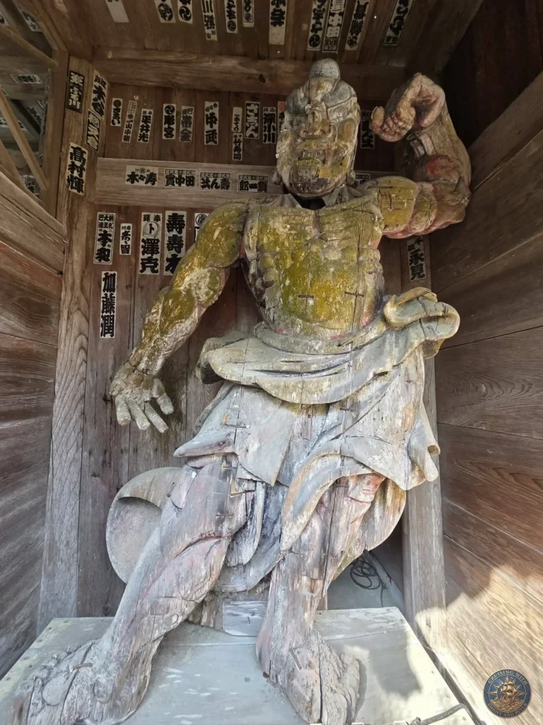 Dynamic wooden Niō guardian statue in a powerful pose at Chikurin Temple in Kochi, Japan. Detailed traditional temple protector figure with vibrant remnants of paint. Kochi Cruise Port Guide | Things to do in Kochi from cruise ship | One day in Kochi Japan itinerary by Danny and Peter.