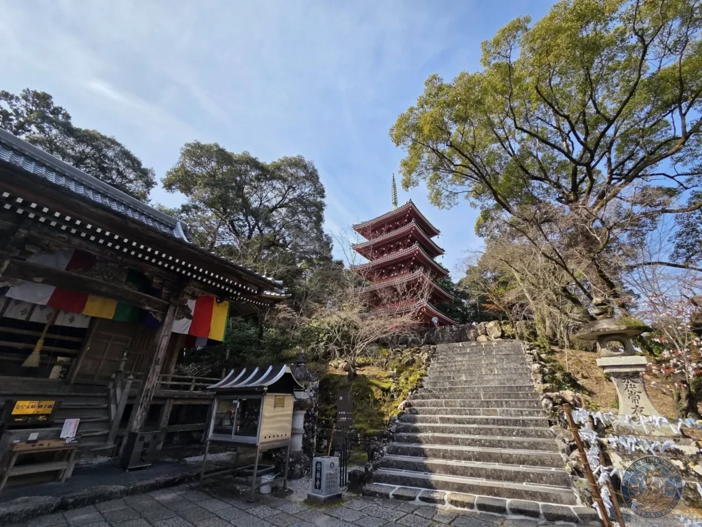 Iconic five-story red pagoda towering above stone stairs and traditional buildings at Chikurin Temple in Kochi, Japan. Stunning view framed by trees under a clear blue sky. Kochi Cruise Port Guide | Things to do in Kochi from cruise ship | One day in Kochi Japan itinerary by Danny and Peter.