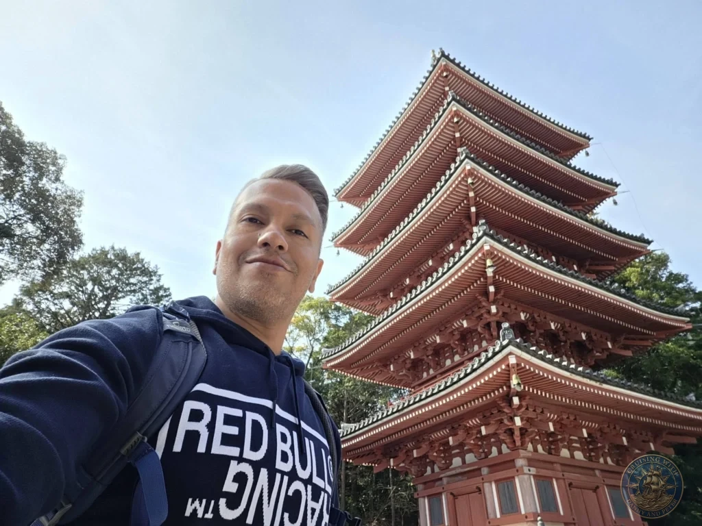 Danny taking a selfie with the iconic five-story red pagoda of Chikurin Temple in Kochi, Japan. Stunning traditional architecture against a clear blue sky. Kochi Cruise Port Guide | Things to do in Kochi from cruise ship | One day in Kochi Japan itinerary by Danny and Peter.