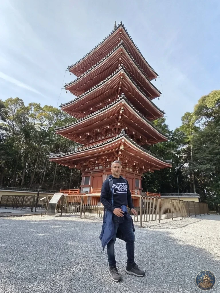 Danny standing in front of the iconic five-story red pagoda at Chikurin Temple in Kochi, Japan. Beautiful traditional architecture with gravel grounds and trees. Kochi Cruise Port Guide | Things to do in Kochi from cruise ship | One day in Kochi Japan itinerary by Danny and Peter.