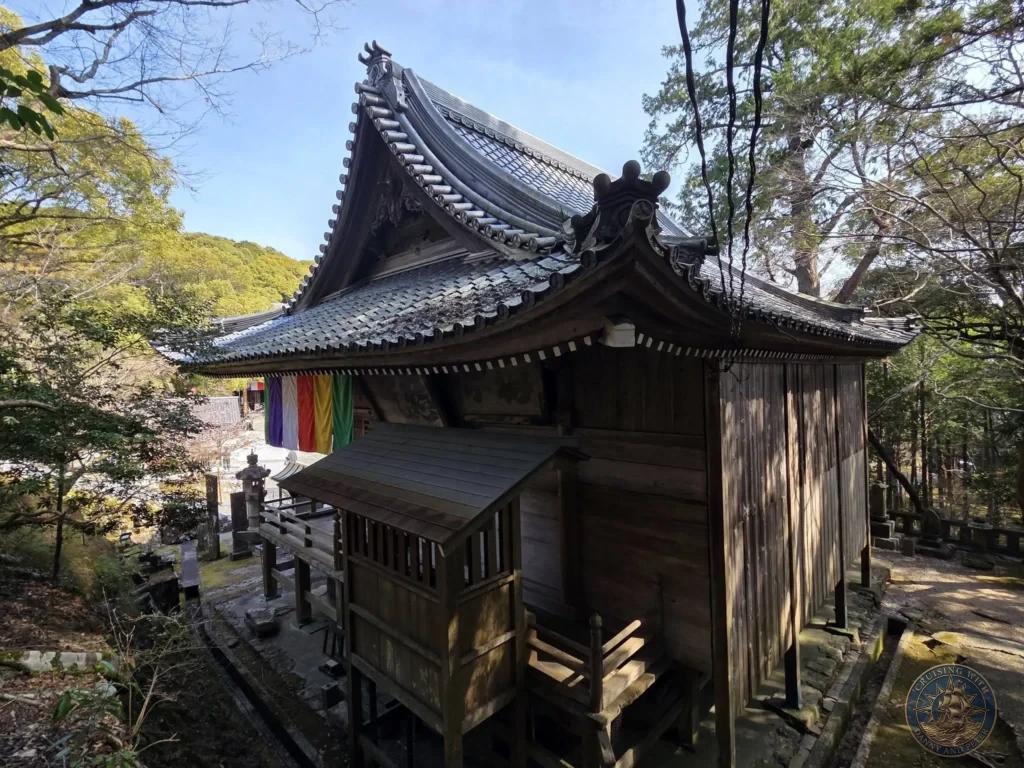 Beautiful traditional wooden temple building with ornate curved roof at Chikurin Temple in Kochi, Japan. Historic architecture surrounded by lush forest. Kochi Cruise Port Guide | Things to do in Kochi from cruise ship | One day in Kochi Japan itinerary by Danny and Peter.