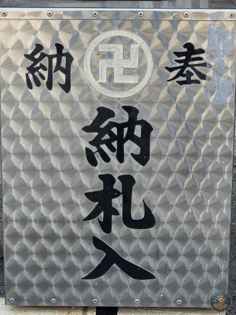 Metal sign reading "奉納札入" on the offering box at Chikurin Temple in Kochi, Japan. Traditional temple donation feature with embossed Japanese characters. Kochi Cruise Port Guide | Things to do in Kochi from cruise ship | One day in Kochi Japan itinerary by Danny and Peter.