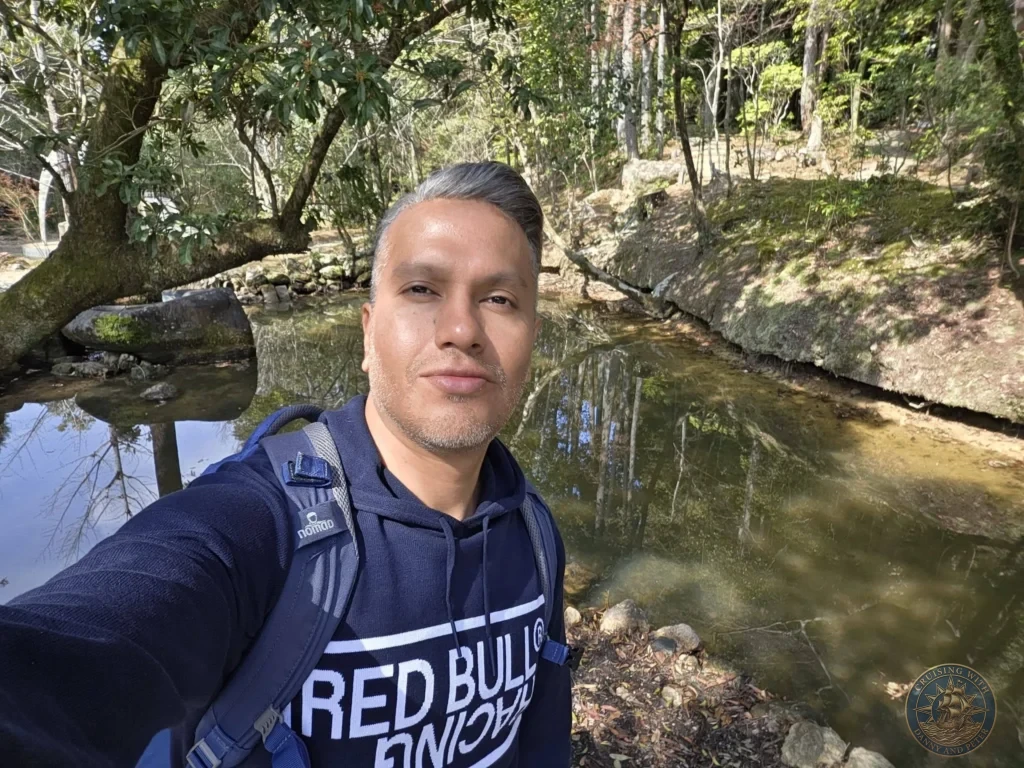 Danny taking a selfie beside a calm pond at Chikurin Temple in Kochi, Japan. Lush forested temple grounds with reflections in the water. Kochi Cruise Port Guide | Things to do in Kochi from cruise ship | One day in Kochi Japan itinerary by Danny and Peter.