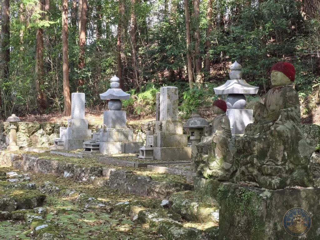 Moss-covered stone Jizo statues, lanterns, and monuments in a forested area at Chikurin Temple in Kochi, Japan. Serene temple memorial grounds surrounded by trees. Kochi Cruise Port Guide | Things to do in Kochi from cruise ship | One day in Kochi Japan itinerary by Danny and Peter.