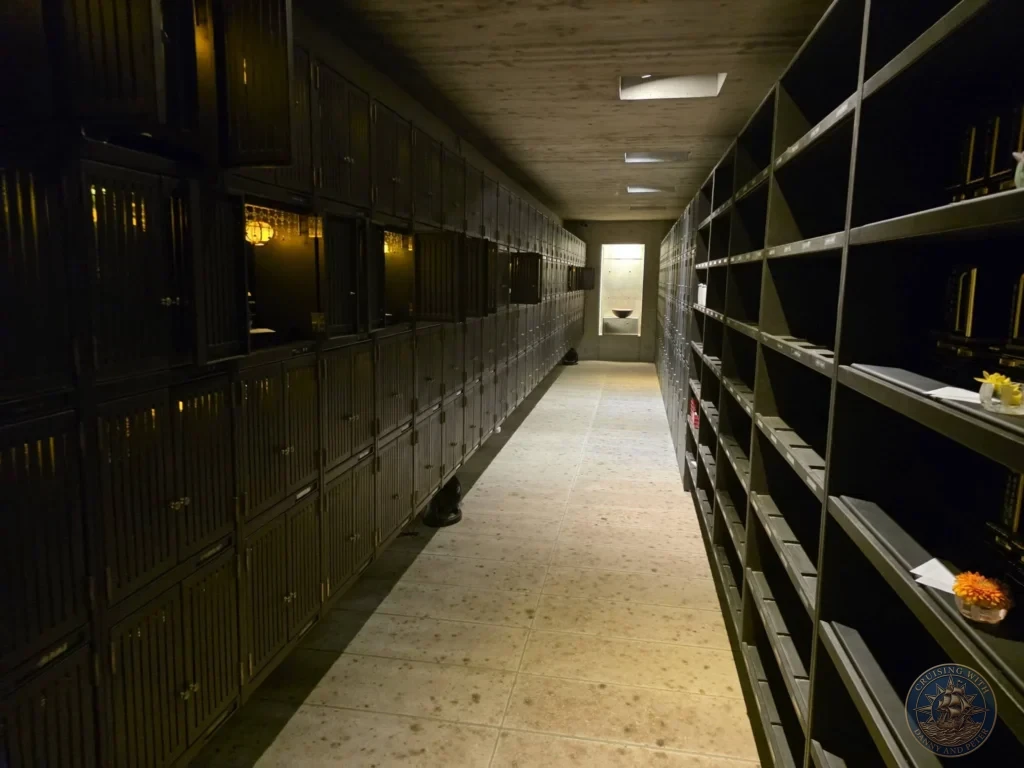 Long corridor with dark wooden memorial lockers and open shelves at Chikurin Temple in Kochi, Japan. Modern columbarium space within the historic temple complex. Kochi Cruise Port Guide | Things to do in Kochi from cruise ship | One day in Kochi Japan itinerary by Danny and Peter.