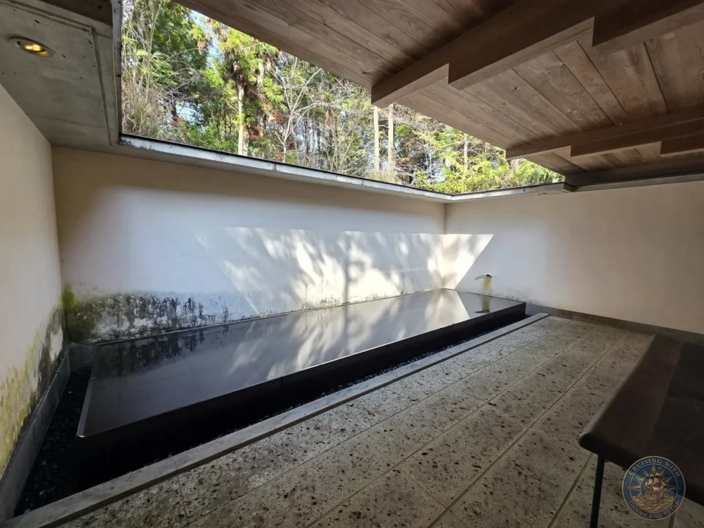 Sleek reflecting pool in a modern concrete and wood pavilion at Chikurin Temple in Kochi, Japan. Contemporary architecture opening to the forest. Kochi Cruise Port Guide | Things to do in Kochi from cruise ship | One day in Kochi Japan itinerary by Danny and Peter.
