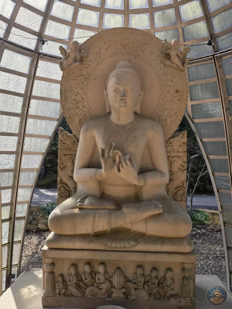 Large seated stone Buddha statue with detailed halo inside a glass pavilion at Chikurin Temple in Kochi, Japan. Impressive Buddhist sculpture. Kochi Cruise Port Guide | Things to do in Kochi from cruise ship | One day in Kochi Japan itinerary by Danny and Peter.