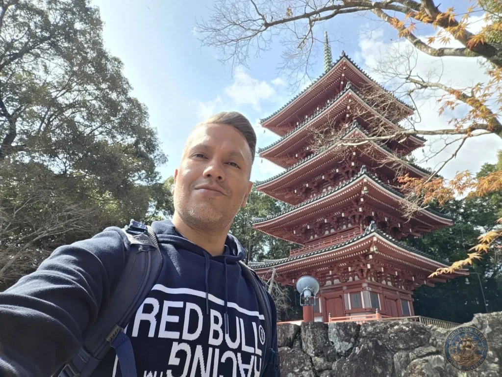 Danny taking a selfie with the iconic five-story red pagoda of Chikurin Temple in Kochi, Japan. Bright sunny day with trees framing the traditional architecture. Kochi Cruise Port Guide | Things to do in Kochi from cruise ship | One day in Kochi Japan itinerary by Danny and Peter.