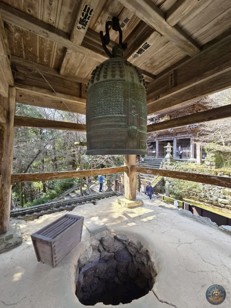 Large bronze temple bell hanging in its traditional wooden tower at Chikurin Temple in Kochi, Japan. Historic bell with scenic views of the temple grounds below. Kochi Cruise Port Guide | Things to do in Kochi from cruise ship | One day in Kochi Japan itinerary by Danny and Peter.