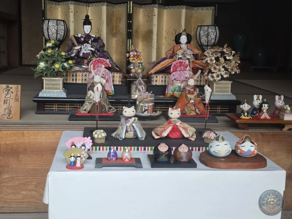 Colorful traditional Japanese doll display featuring Emperor and Empress figures with rabbit, cat, and Daruma dolls at the Chiran Doll & Toy Museum in the Chiran Samurai District. Wonderful cultural stop during a Kagoshima cruise excursion. Kagoshima Cruise Port Guide | Things to do in Kagoshima from cruise ship | One day in Kagoshima Japan itinerary by Danny and Peter.