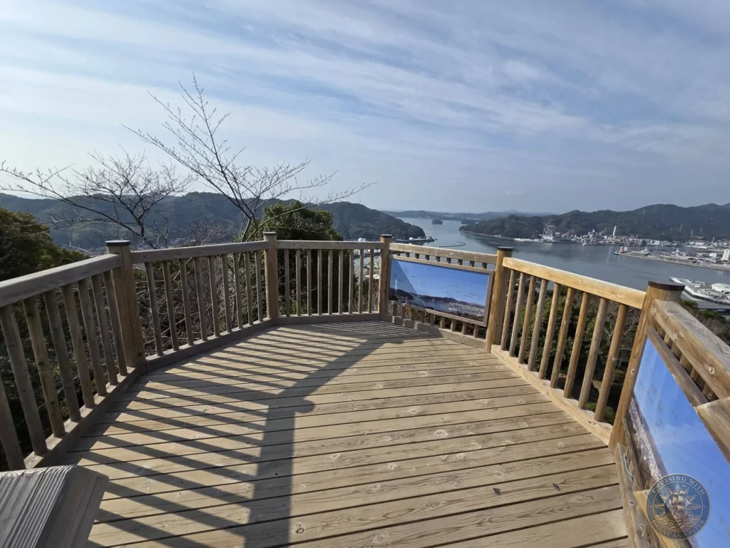 Panoramic view from the wooden deck of Godaisan Observatory overlooking Kochi harbor, city skyline, and mountains in Kochi, Japan. Scenic lookout point. Kochi Cruise Port Guide | Things to do in Kochi from cruise ship | One day in Kochi Japan itinerary by Danny and Peter.