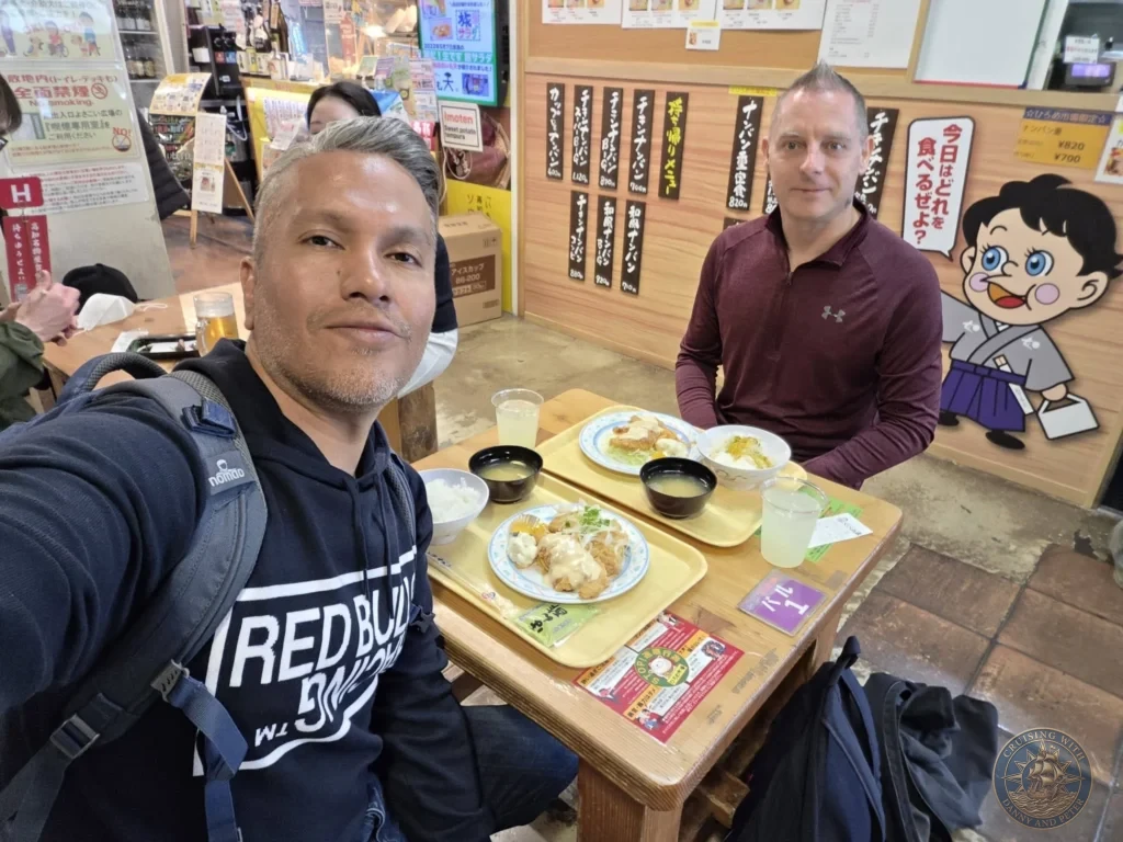 Danny and Peter taking a selfie while enjoying lunch at Hirome Market in Kochi, Japan. Bustling food court with trays of local dishes. Kochi Cruise Port Guide | Things to do in Kochi from cruise ship | One day in Kochi Japan itinerary by Danny and Peter.