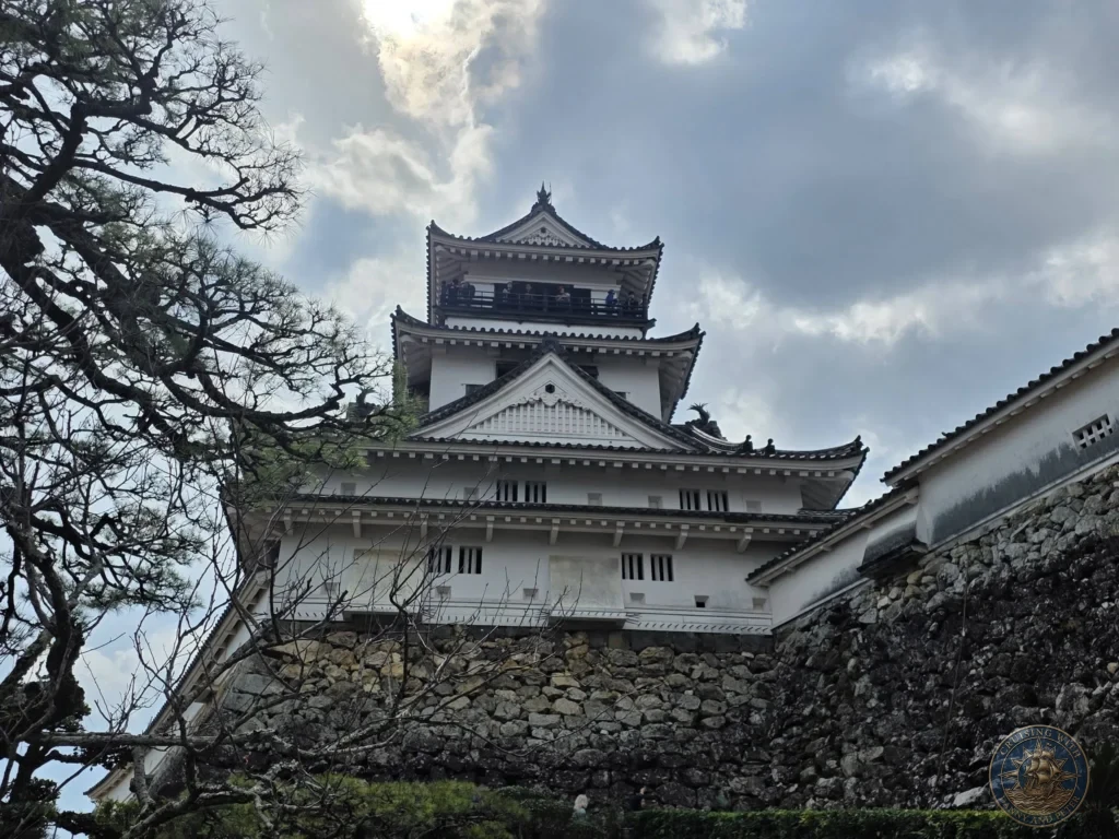 Dramatic low-angle view of Kochi Castle keep towering above stone walls in Kochi, Japan. Iconic historic castle architecture against a cloudy sky. Kochi Cruise Port Guide | Things to do in Kochi from cruise ship | One day in Kochi Japan itinerary by Danny and Peter.