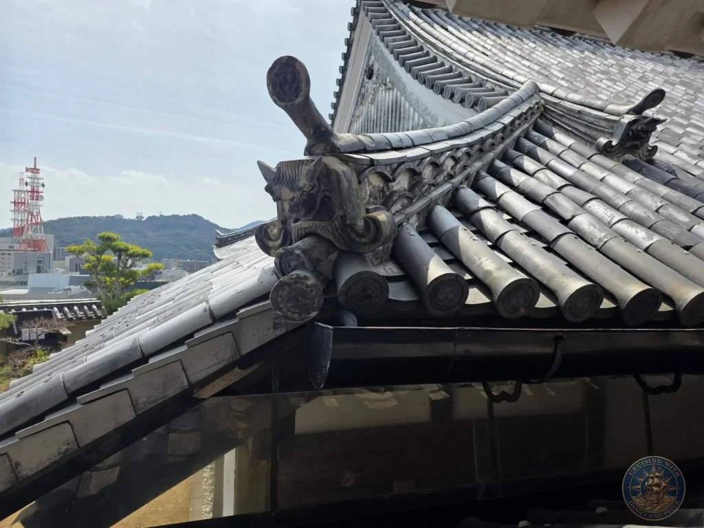 Intricate traditional gray roof tiles and ornate onigawara demon tile on Kochi Castle in Kochi, Japan. Fine example of historic Japanese castle architecture. Kochi Cruise Port Guide | Things to do in Kochi from cruise ship | One day in Kochi Japan itinerary by Danny and Peter.