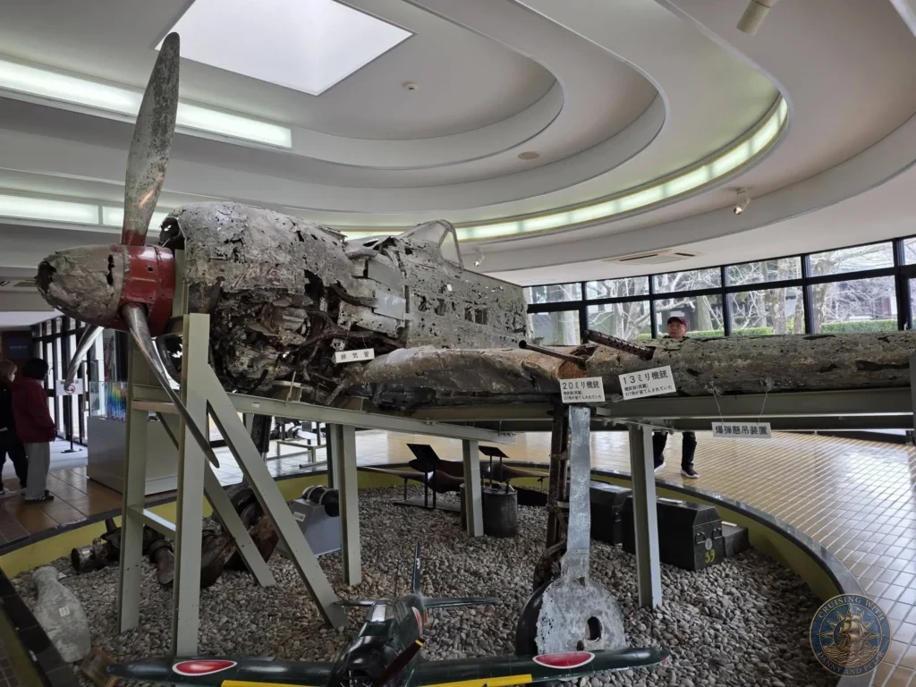 Heavily damaged kamikaze aircraft wreckage on indoor display at the Chiran Peace Museum for Kamikaze Pilots. Powerful exhibit showcasing the reality of the Special Attack Forces in Chiran Samurai District, Kagoshima, Japan. Kagoshima Cruise Port Guide | Things to do in Kagoshima from cruise ship | One day in Kagoshima Japan itinerary by Danny and Peter.