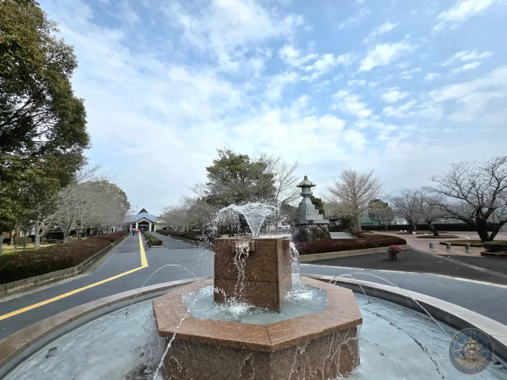 Elegant fountain with spraying water at the entrance plaza of the Chiran Peace Museum for Kamikaze Pilots, with stone lantern and museum building in the background. Peaceful approach to the historic memorial site in Chiran Samurai District, Kagoshima, Japan. Kagoshima Cruise Port Guide | Things to do in Kagoshima from cruise ship | One day in Kagoshima Japan itinerary by Danny and Peter.