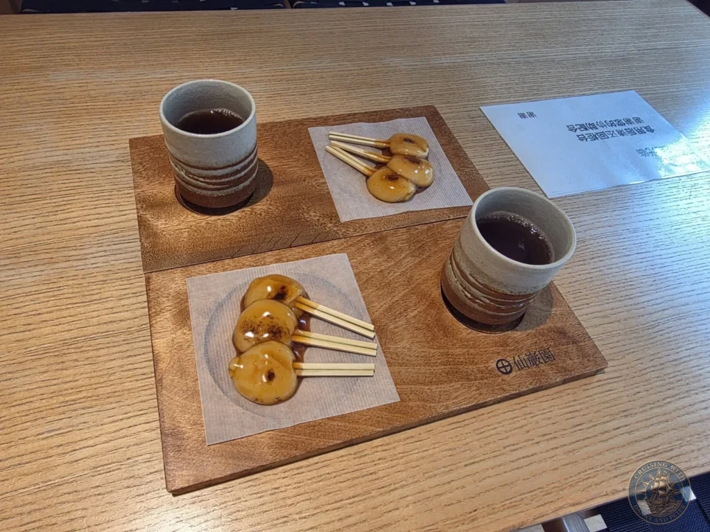 Traditional mitarashi dango (grilled rice dumplings with sweet soy glaze) and green tea served at Sengan-en (Iso Garden) in Kagoshima. Delightful Japanese refreshment break while enjoying the historic UNESCO garden and Sakurajima views. Kagoshima Cruise Port Guide | Things to do in Kagoshima from cruise ship | One day in Kagoshima Japan itinerary by Danny and Peter.