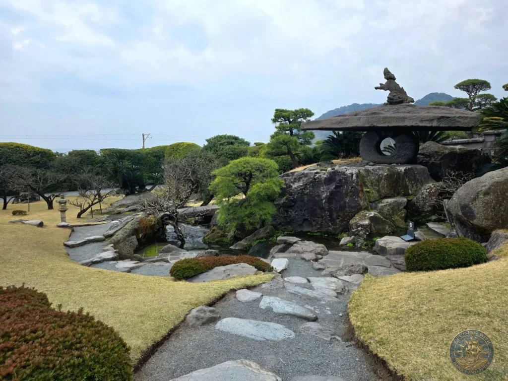 Beautiful pond and rock garden with traditional stone lantern, stepping stones, and manicured trees at Sengan-en (Iso Garden), the historic UNESCO World Heritage samurai villa overlooking Sakurajima volcano in Kagoshima, Japan. Kagoshima Cruise Port Guide | Things to do in Kagoshima from cruise ship | One day in Kagoshima Japan itinerary by Danny and Peter.