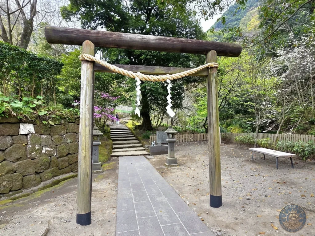 Traditional wooden torii gate with sacred shimenawa rope and shide streamers at Sengan-en (Iso Garden), the historic UNESCO World Heritage samurai villa in Kagoshima, Japan. Peaceful entrance leading into the lush garden with forested hills. Kagoshima Cruise Port Guide | Things to do in Kagoshima from cruise ship | One day in Kagoshima Japan itinerary by Danny and Peter.