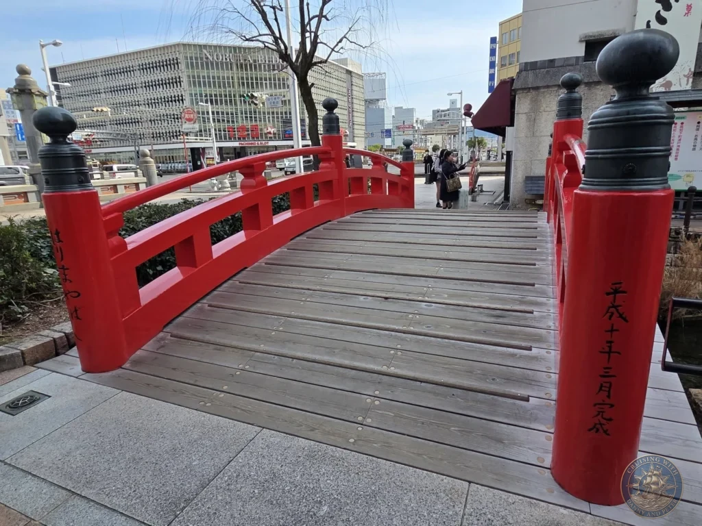 Vibrant red traditional bridge in Kochi, Japan. Pedestrian crossing with urban background. Kochi Cruise Port Guide | Things to do in Kochi from cruise ship | One day in Kochi Japan itinerary by Danny and Peter.