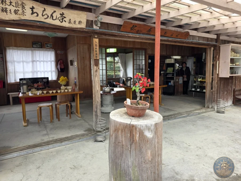 Traditional wooden tea house interior at Tsukiyama-sensui Garden 7 (Mori Teien) in Chiran Samurai District, Kagoshima, Japan. Rustic tables, stools, and garden entrance with Japanese signage. Kagoshima Cruise Port Guide | Things to do in Kagoshima from cruise ship | One day in Kagoshima Japan itinerary by Danny and Peter.