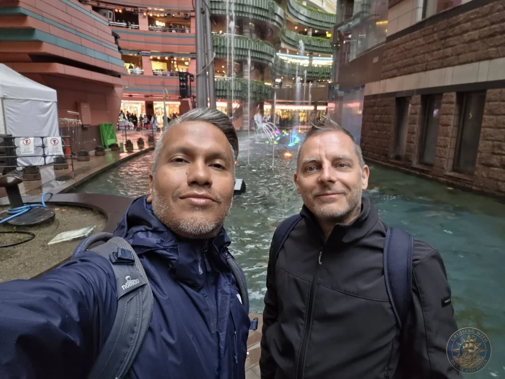 Danny and Peter taking a selfie with the water fountain at Canal City Hakata in Fukuoka, Japan. Popular cruise port attraction. Fukuoka Cruise Port Guide | Things to do in Fukuoka from cruise ship | One day in Fukuoka Japan itinerary by Danny and Peter.