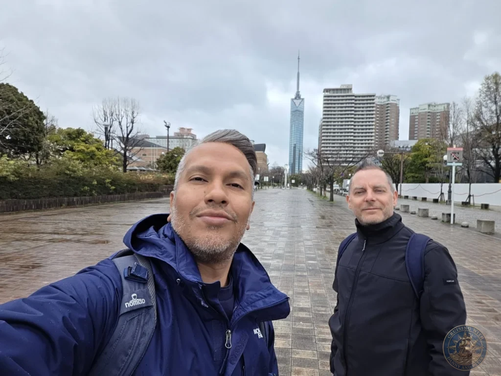 Danny and Peter taking a selfie with Fukuoka Tower and modern skyline in the background, Japan. Cruise port exploration. Fukuoka Cruise Port Guide | Things to do in Fukuoka from cruise ship | One day in Fukuoka Japan itinerary by Danny and Peter.