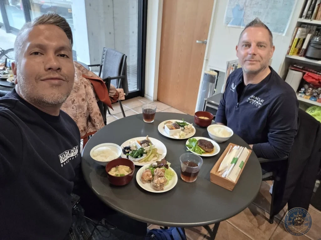 Danny and Peter smiling at the table with a full traditional Japanese lunch spread in Fukuoka, Japan. Local dining experience. Fukuoka Cruise Port Guide | Things to do in Fukuoka from cruise ship | One day in Fukuoka Japan itinerary by Danny and Peter.