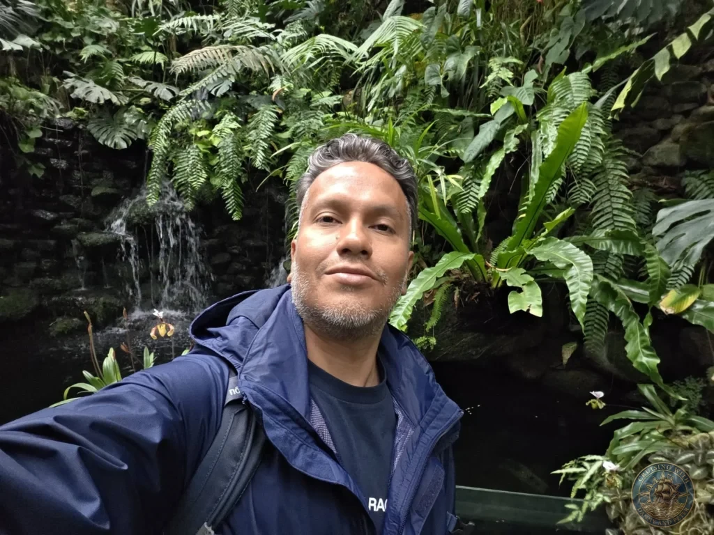 Danny taking a selfie in front of lush mossy fern wall with waterfall at Makino Botanical Garden in Kochi, Japan. Tropical greenhouse feature. Kochi Cruise Port Guide | Things to do in Kochi from cruise ship | One day in Kochi Japan itinerary by Danny and Peter.