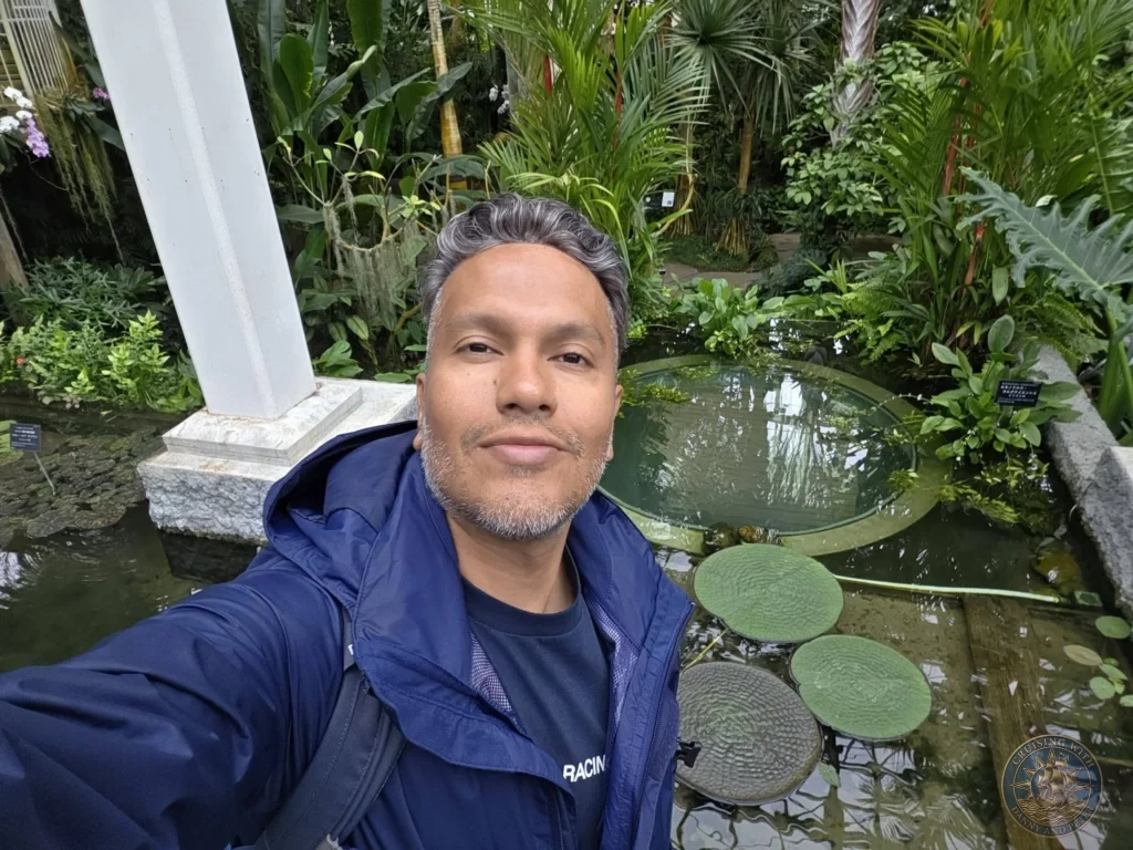 Danny taking a selfie by circular lily pad pond in the greenhouse at Makino Botanical Garden in Kochi, Japan. Tropical water feature. Kochi Cruise Port Guide | Things to do in Kochi from cruise ship | One day in Kochi Japan itinerary by Danny and Peter.