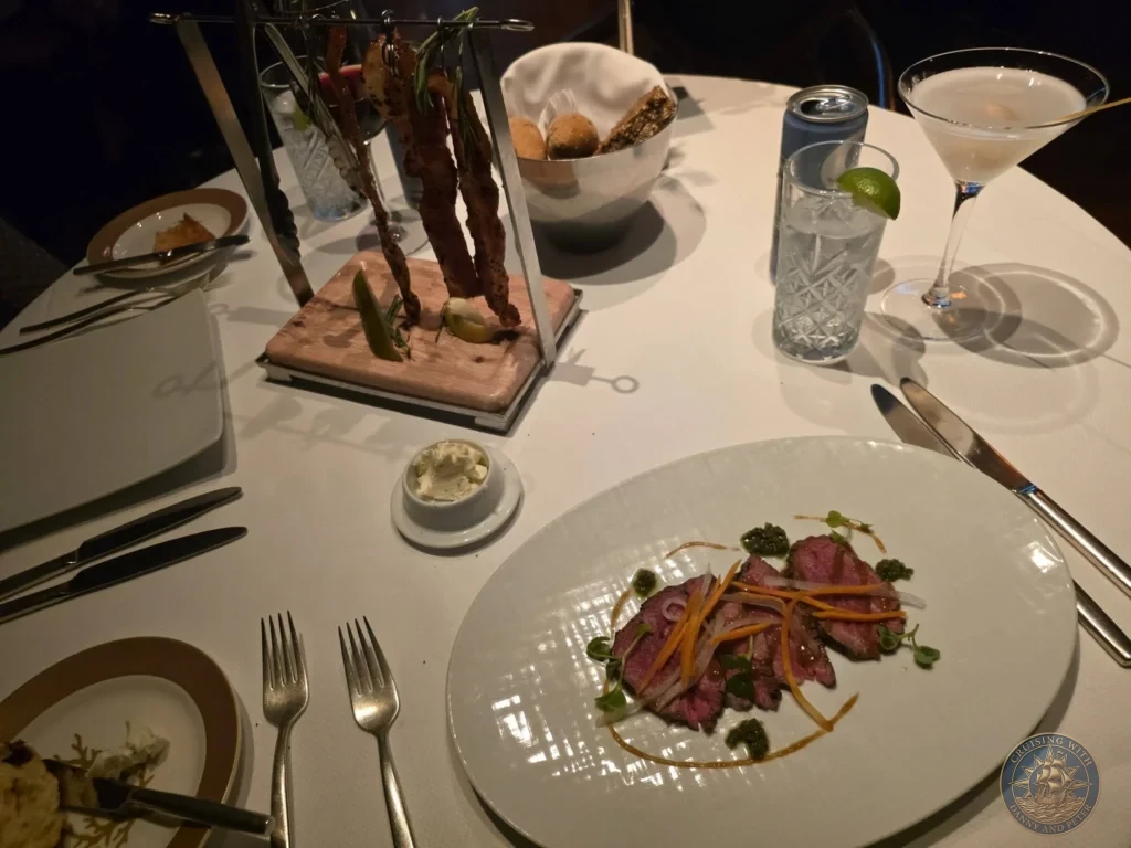 Steak dish with bacon skewer and martini at Pinnacle Grill on Holland America Westerdam in Kochi, Japan. Cruise ship fine dining. Kochi Cruise Port Guide | Things to do in Kochi from cruise ship | One day in Kochi Japan itinerary by Danny and Peter.