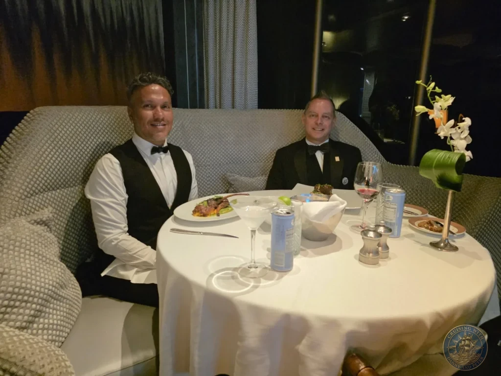 Danny and Peter seated at elegant table in Pinnacle Grill on Holland America Westerdam in Kochi, Japan. Cruise ship fine dining. Kochi Cruise Port Guide | Things to do in Kochi from cruise ship | One day in Kochi Japan itinerary by Danny and Peter.